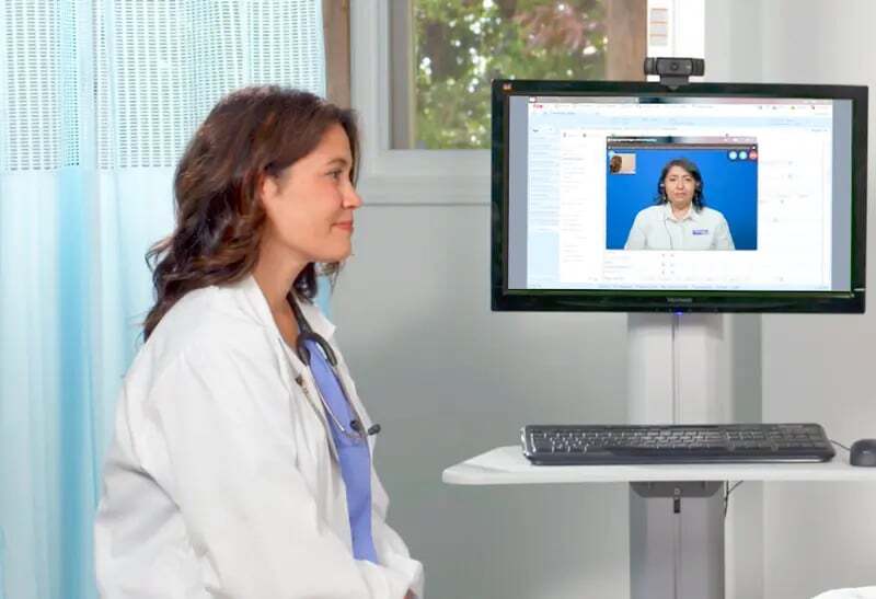 A doctor meets with a patient with the support of a video interpreter.